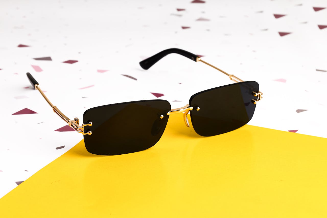 Home Elegant black sunglasses with gold accents on a vibrant yellow background.